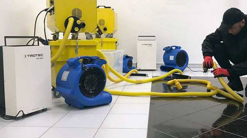 Techniker trocknet Estrich und Dämmschicht mittels Vakuumturbinen und Schlauchsystem in Grasbrunn