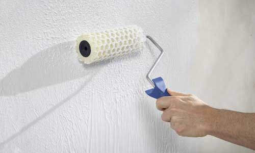 Maler streicht eine Wand nach Wasserschaden in Grasbrunn